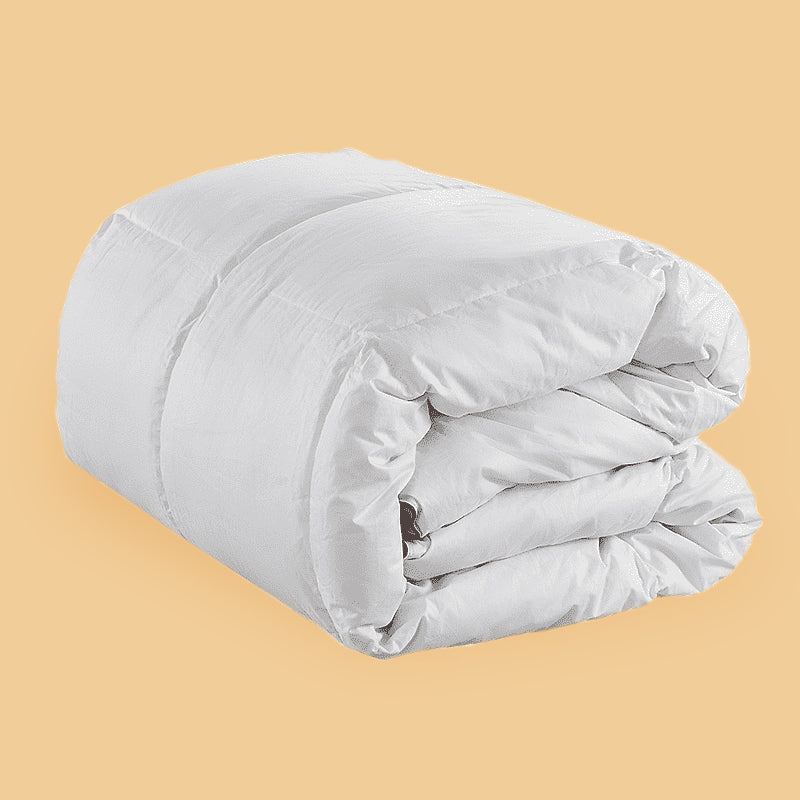 A white Hamuq down duvet folded and rolled on a yellow background