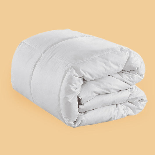 A white Hamuq down duvet folded and rolled on a yellow background